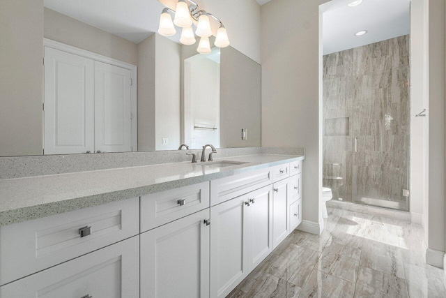 bathroom with toilet, a shower with door, vanity, and a notable chandelier