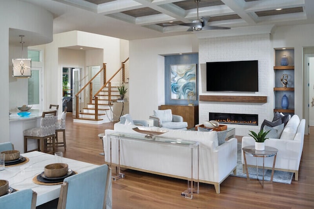 living room with coffered ceiling, ceiling fan, a fireplace, beamed ceiling, and wood-type flooring