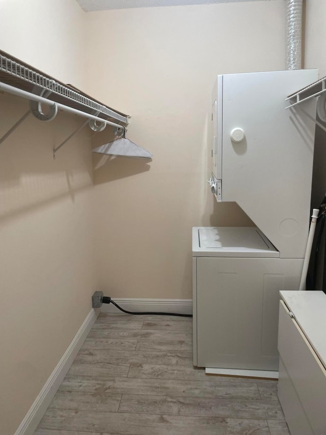 laundry room with light hardwood / wood-style floors and stacked washer / dryer