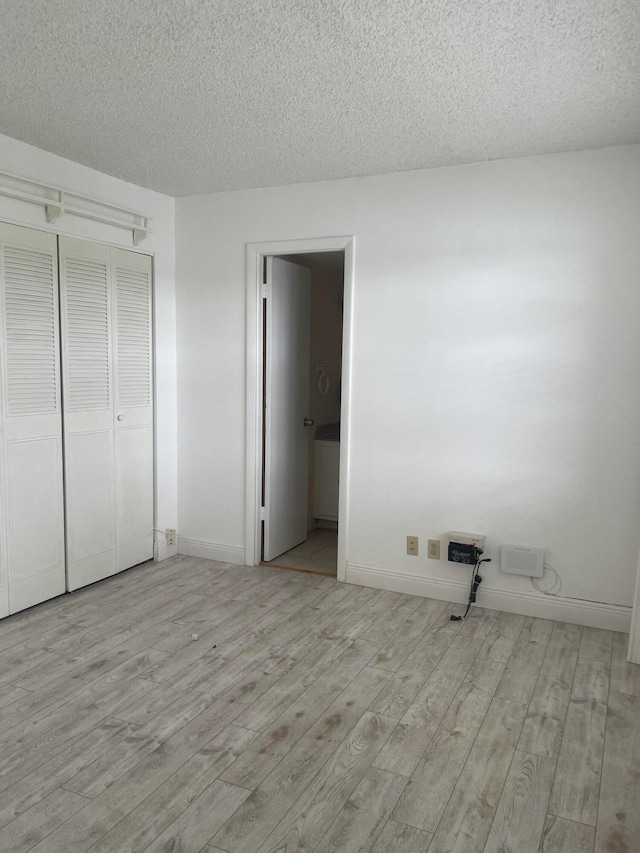 unfurnished bedroom featuring a textured ceiling, a closet, and light hardwood / wood-style floors