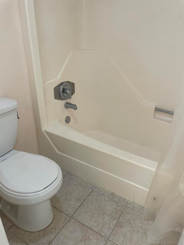 bathroom featuring washtub / shower combination, tile patterned flooring, and toilet