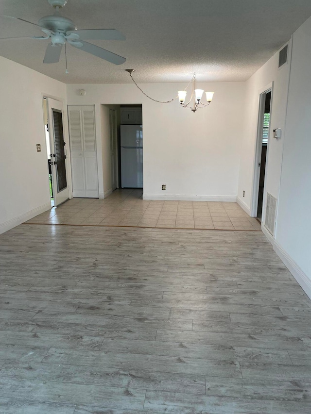 unfurnished room featuring ceiling fan with notable chandelier and light hardwood / wood-style flooring