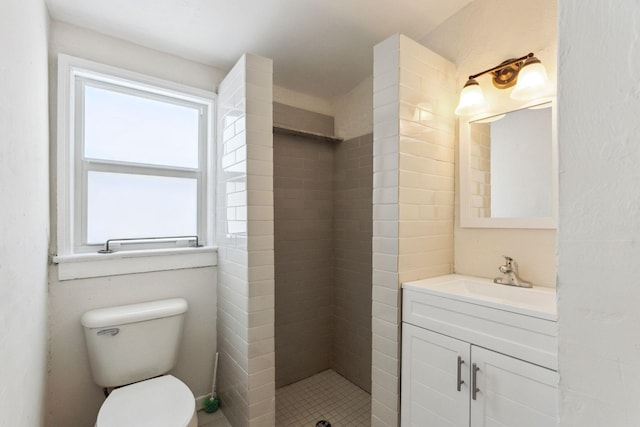 bathroom with vanity, toilet, and a tile shower