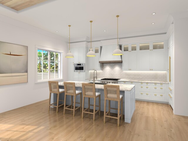 kitchen featuring light hardwood / wood-style flooring, white cabinets, backsplash, custom exhaust hood, and an island with sink