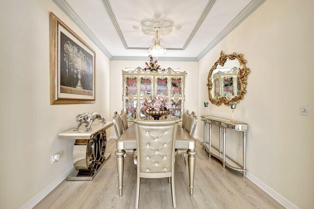 dining room with a tray ceiling, light hardwood / wood-style flooring, and ornamental molding