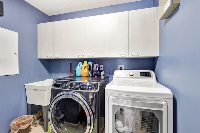 laundry area featuring cabinets, a textured ceiling, and washer and dryer