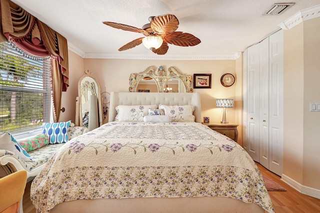 bedroom with ceiling fan, a closet, crown molding, and light wood-type flooring