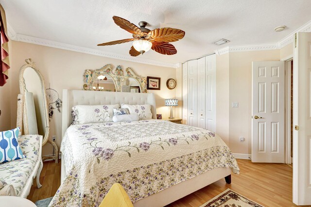 bedroom featuring hardwood / wood-style flooring, ceiling fan, ornamental molding, and a closet