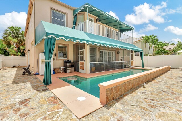 rear view of property featuring a fenced in pool, a balcony, and a patio