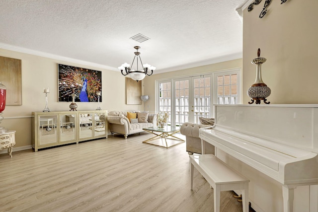 living room featuring light wood-type flooring, a textured ceiling, an inviting chandelier, and ornamental molding