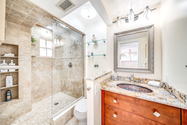 bathroom with tiled shower, vanity, and toilet