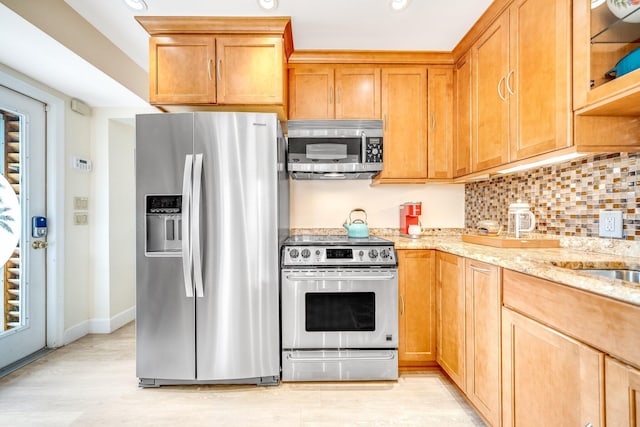 kitchen with backsplash, light stone countertops, and appliances with stainless steel finishes