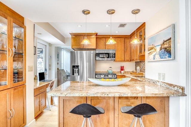 kitchen featuring a kitchen bar, appliances with stainless steel finishes, and light stone counters