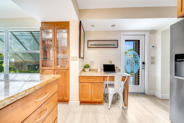 office space with a healthy amount of sunlight, built in desk, and light hardwood / wood-style floors