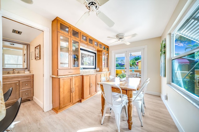 dining area featuring french doors, light wood-type flooring, ceiling fan, and sink