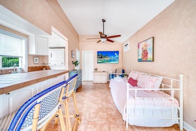 bedroom featuring stacked washer / dryer, ceiling fan, and light tile patterned floors