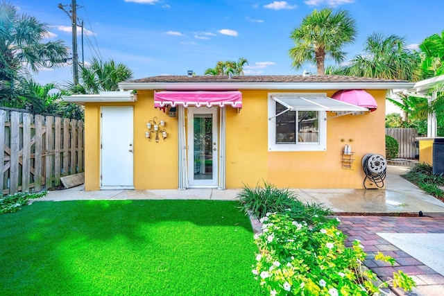 back of house with a yard and a patio