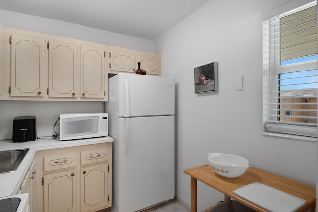 kitchen with white appliances, light brown cabinetry, and sink