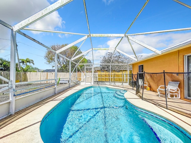 view of swimming pool featuring glass enclosure and a patio area