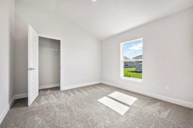 carpeted empty room featuring lofted ceiling