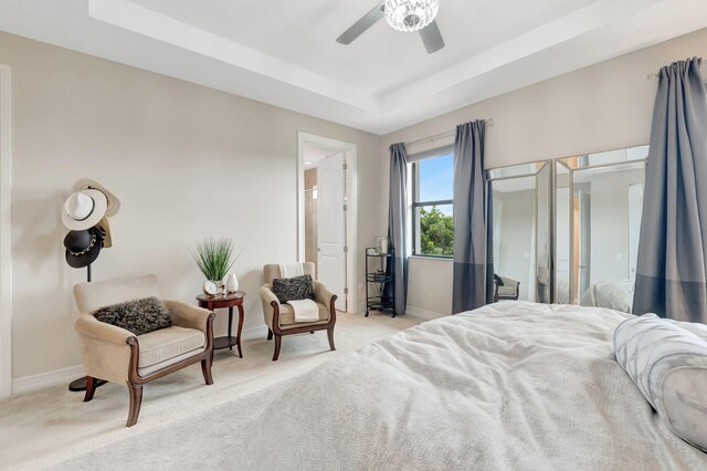 carpeted bedroom with ceiling fan and a raised ceiling