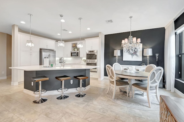 kitchen with a large island, white cabinets, decorative light fixtures, and stainless steel appliances