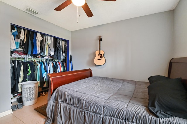 bedroom with ceiling fan, tile patterned floors, and a closet