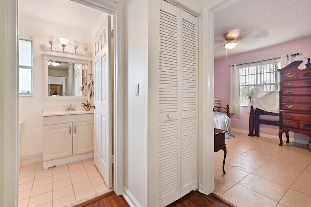 hallway with sink, a textured ceiling, and light tile patterned floors