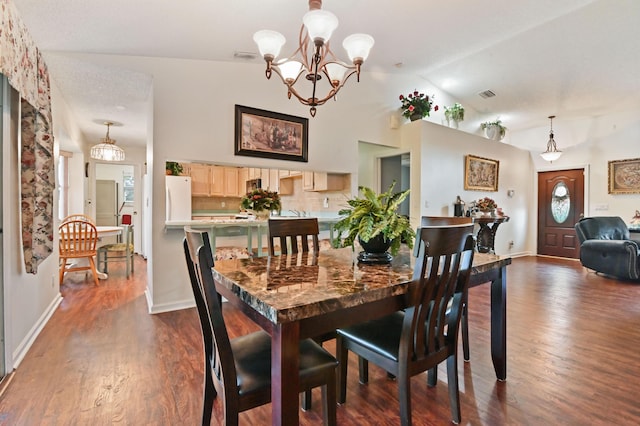 dining area with a chandelier, lofted ceiling, and dark hardwood / wood-style floors