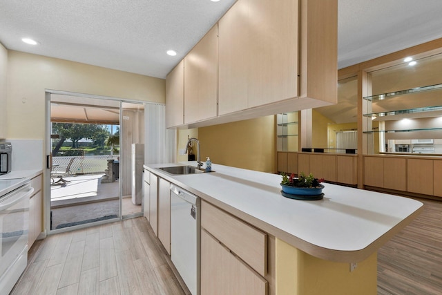 1217 NW Sun Terrace Cir Unit B, Port Saint Lucie, FL 34986 - kitchen with white appliances, a sink, light countertops, a peninsula, and light wood-style floors