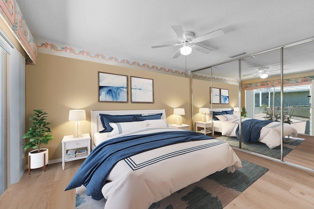 bedroom featuring ceiling fan, light wood-type flooring, a textured ceiling, and a closet