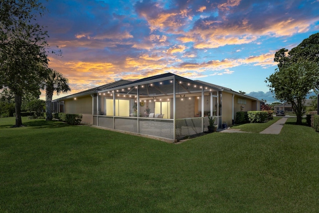 property exterior at dusk featuring a lanai and a yard