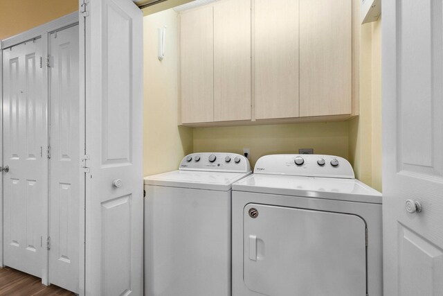 washroom featuring dark hardwood / wood-style flooring, cabinets, and washing machine and clothes dryer