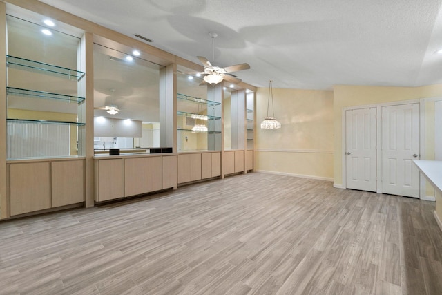 interior space featuring a textured ceiling, lofted ceiling, and light wood-type flooring