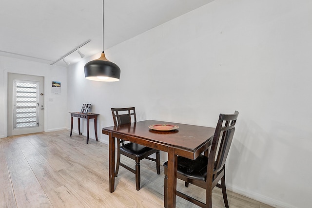 dining space with light hardwood / wood-style flooring and track lighting