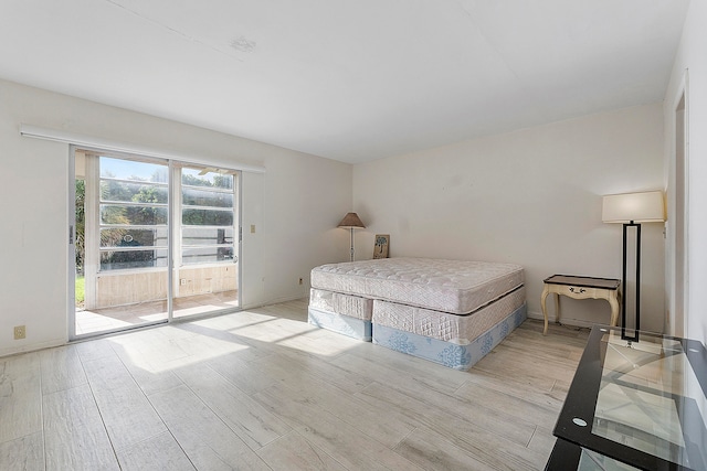 bedroom with access to exterior, multiple windows, and light hardwood / wood-style floors