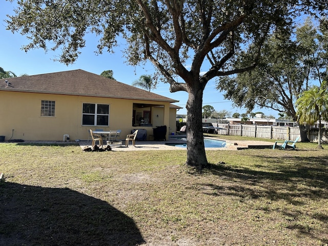 back of property with a fenced in pool, a patio area, and a yard