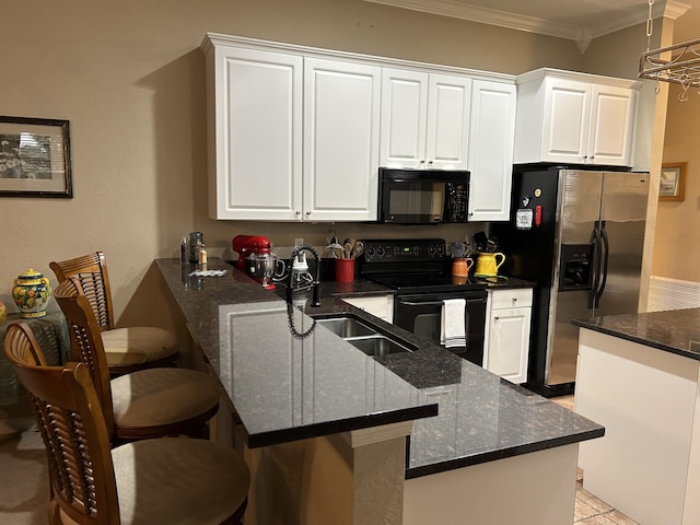 kitchen with kitchen peninsula, a breakfast bar, white cabinetry, and black appliances