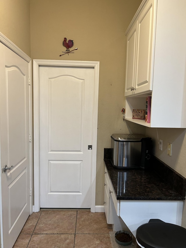 kitchen with white cabinetry and dark stone countertops