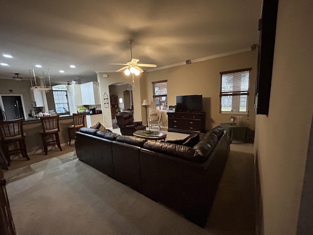 living room with plenty of natural light, ceiling fan, crown molding, and light carpet