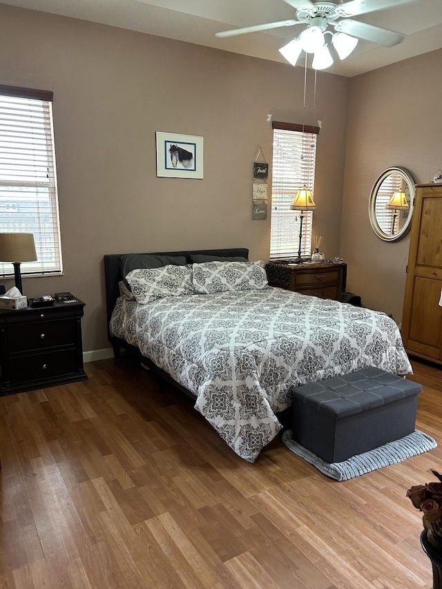 bedroom with multiple windows, ceiling fan, and wood-type flooring