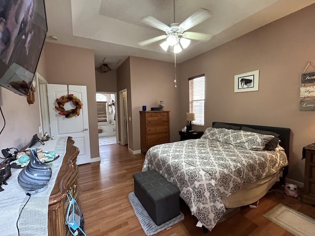 bedroom with a raised ceiling, ceiling fan, and wood-type flooring