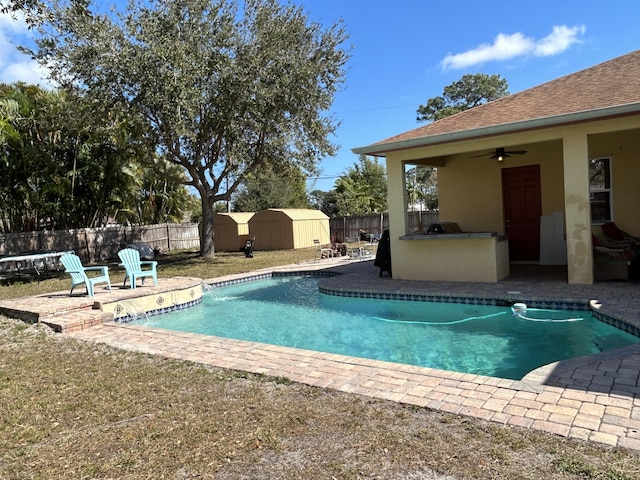 view of pool with a bar, a patio, a storage unit, and ceiling fan