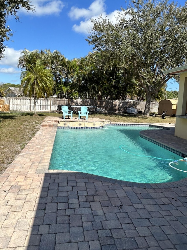 view of pool with a patio and a storage unit