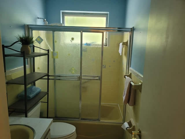 full bathroom featuring vanity, enclosed tub / shower combo, and toilet