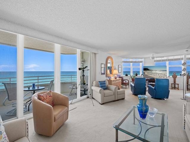 carpeted living room with a water view and a textured ceiling