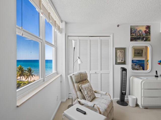 living area with carpet flooring, a water view, and a textured ceiling