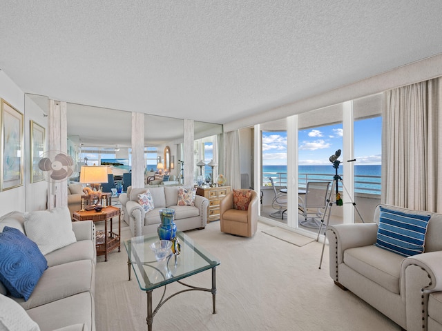 living room with a water view, a textured ceiling, a healthy amount of sunlight, and light colored carpet