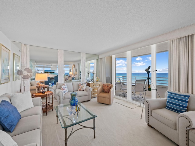 carpeted living room with a water view and a textured ceiling