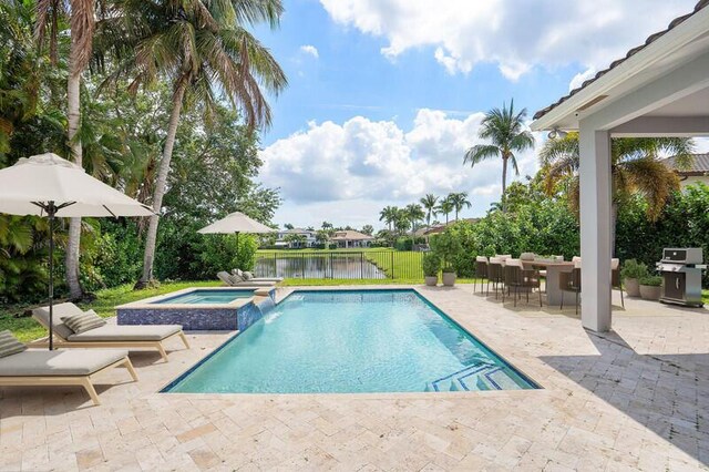 view of pool with a patio area, a water view, an in ground hot tub, and grilling area